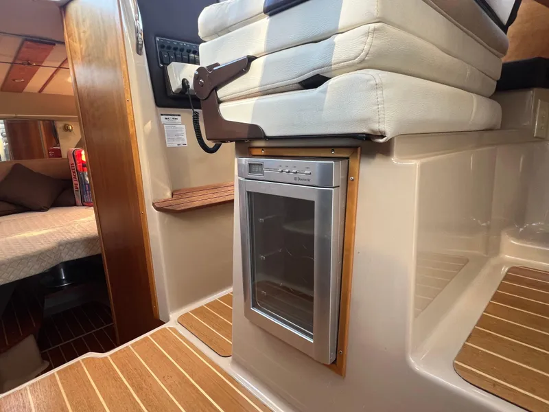 Slide: The Image of Interior of a 2016 Cutwater C28 boat featuring a compact fridge and cozy cabin area. - 36