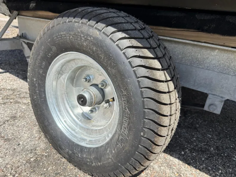 Slide: The Image of Trailer wheel for 2002 Hurricane FunDeck 211 O/B boat on asphalt surface. - 24