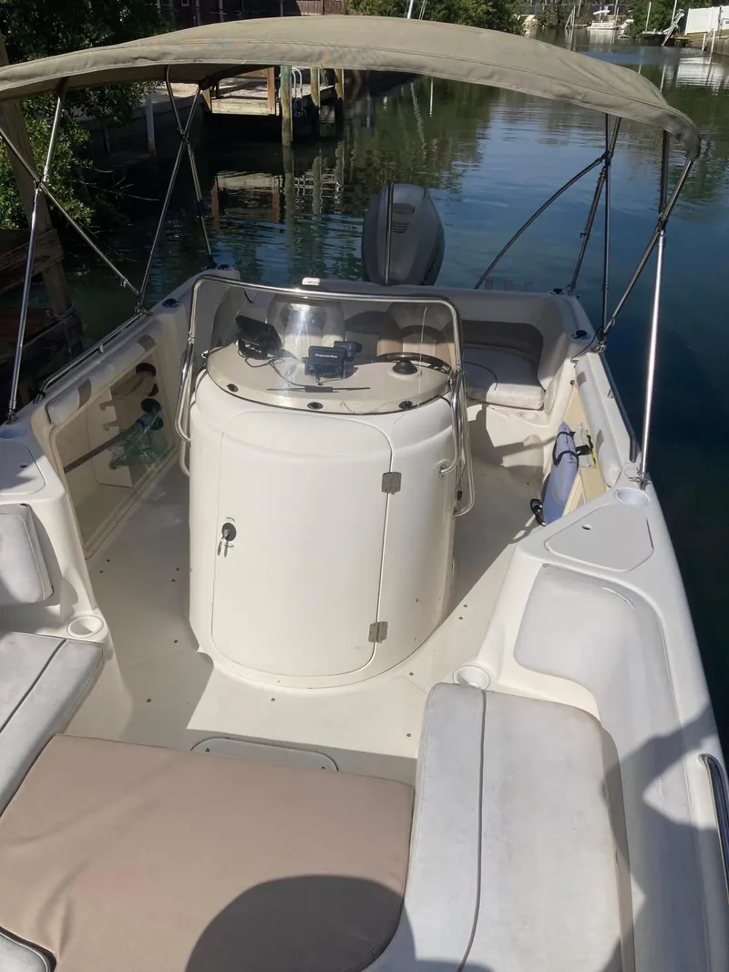 Slide: The Image of 2002 Hurricane FunDeck 211 O/B boat with canopy, docked on calm water. - 30