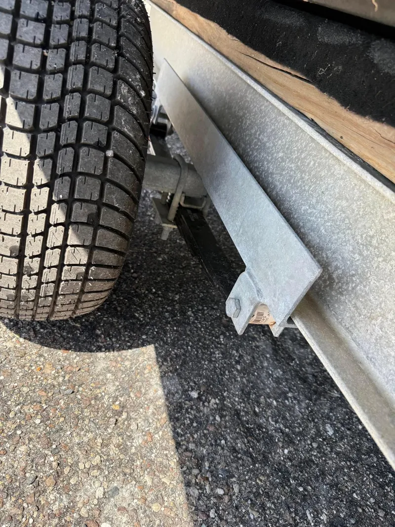 Slide: The Image of 2002 Hurricane FunDeck 211 O/B trailer wheel and frame on asphalt surface. - 5