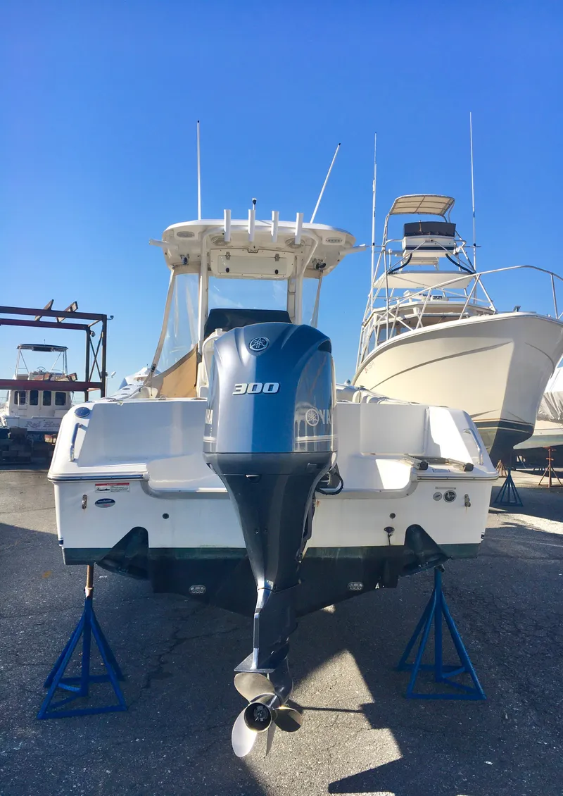 Slide: The Image of 2014 Sea Hunt Gamefish 25 boat with 300 HP engine on stands, marina background. - 6