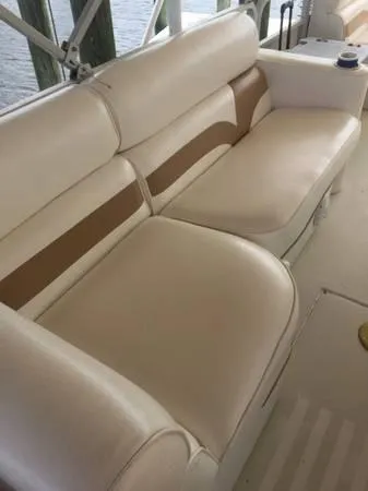 Slide: The Image of 1997 Sylvan Deck Boat interior with beige and brown cushioned seating. - 11