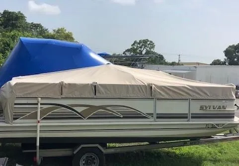 Slide: The Image of 1997 Sylvan Deck Boat with cover, parked on trailer, outdoors. - 13