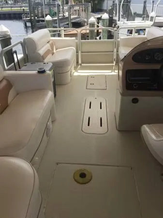 Slide: The Image of 1997 Sylvan Deck Boat interior with beige seating and control panel, docked at marina. - 7