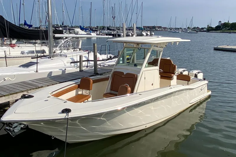 Slide: The Image of 2016 Scout 255 LXF boat docked in a marina with sailboats in the background. - 1