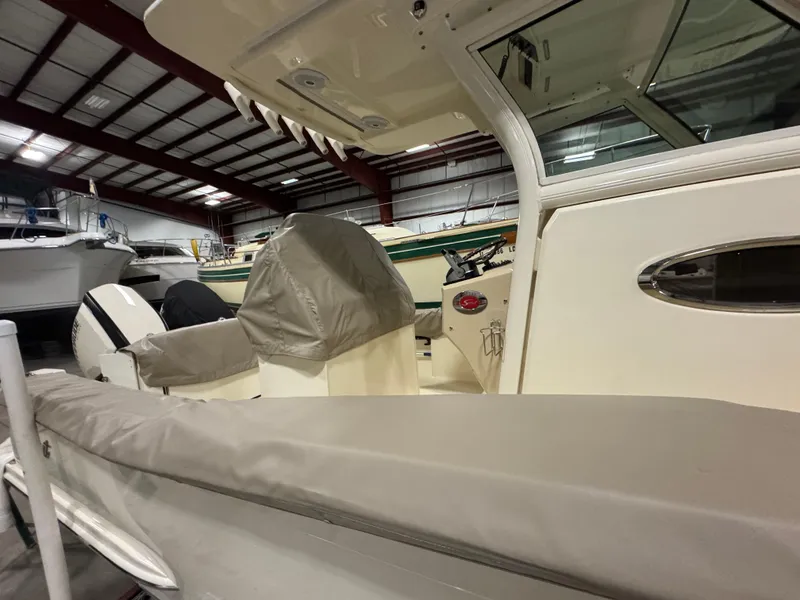 Slide: The Image of 2016 Scout 255 LXF boat interior in a storage facility, featuring covered seating and helm. - 18