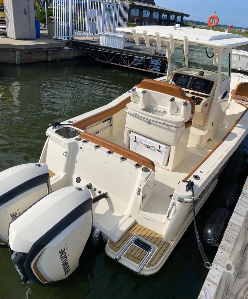 Slide: The Image of 2016 Scout 255 LXF boat docked with dual Evinrude engines, featuring a spacious deck and seating. - 2