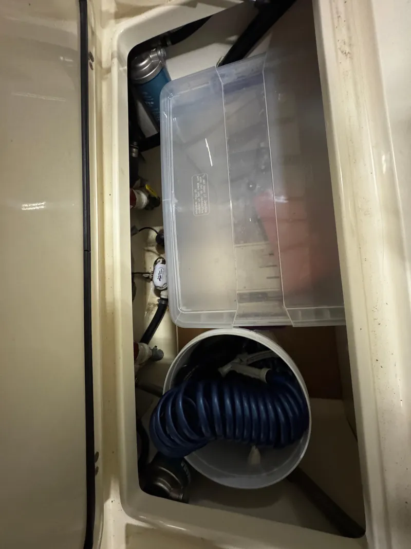 Slide: The Image of Storage compartment of 2016 Scout 255 LXF boat with hose and container. - 24