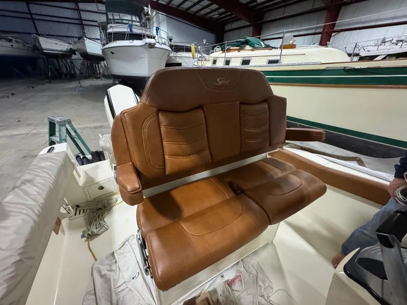 Slide: The Image of 2016 Scout 255 LXF boat with brown leather seating in a storage facility. - 33