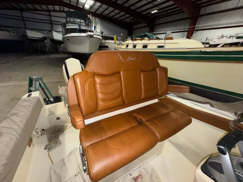 Slide: The Image of 2016 Scout 255 LXF boat with brown leather seating in a storage facility. - 34