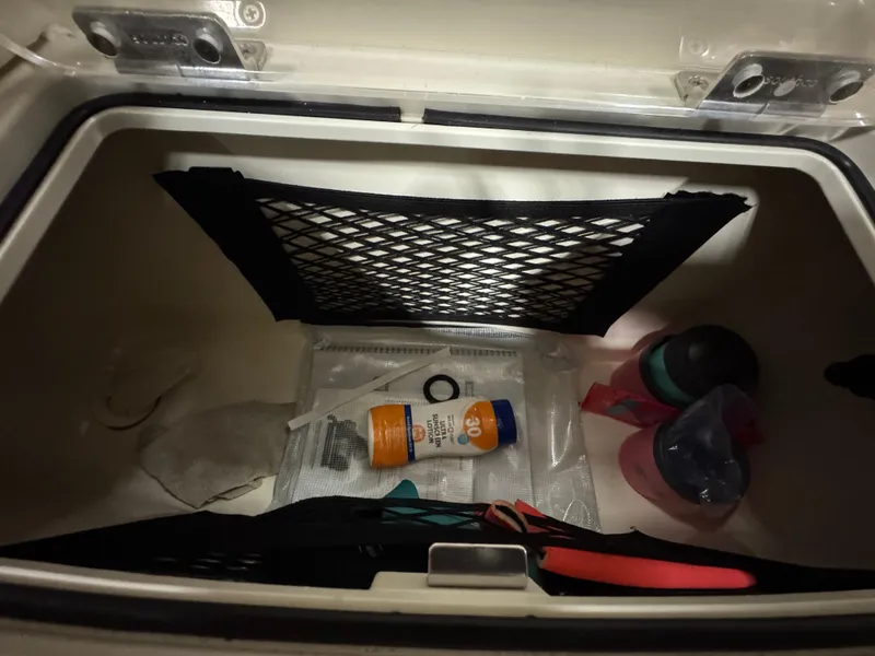 Slide: The Image of Storage compartment in a 2016 Scout 255 LXF boat with various items inside. - 37