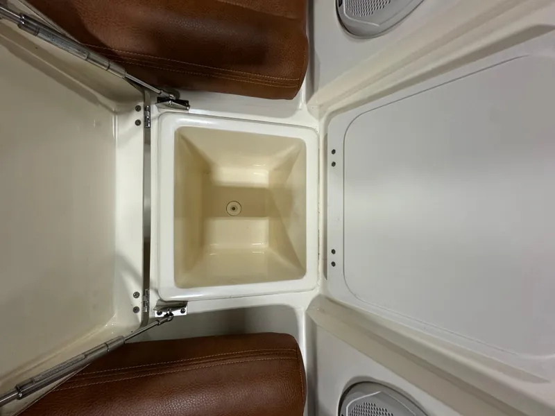 Slide: The Image of 2016 Scout 255 LXF boat storage compartment with brown cushions and speakers. - 40
