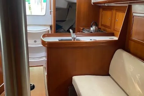 Slide: The Image of Interior of 2006 Beneteau Oceanis Clipper 323 yacht, featuring a compact kitchen and seating area. - 12