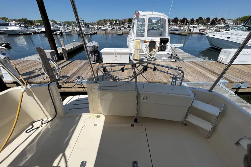 Slide: The Image of 2005 Mainship 400 Trawler docked at marina, showcasing spacious deck and nearby boats. - 11