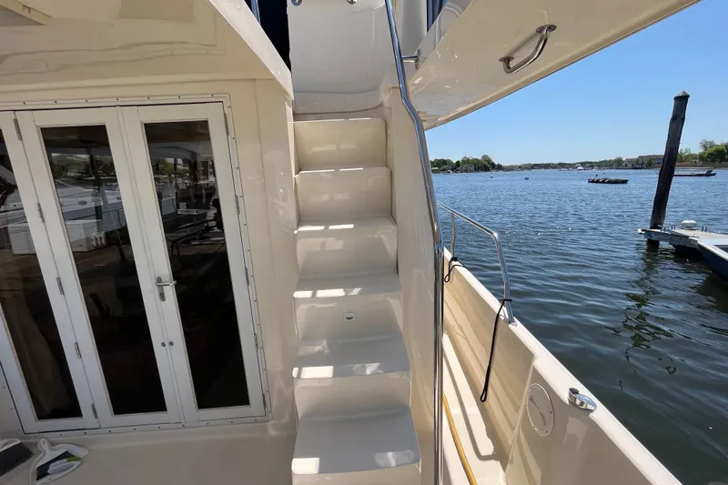 Slide: The Image of 2005 Mainship 400 Trawler with stairs, docked by a serene lake under clear skies. - 12