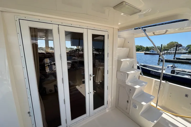 Slide: The Image of 2005 Mainship 400 Trawler with glass doors and exterior stairs, docked by the water. - 15