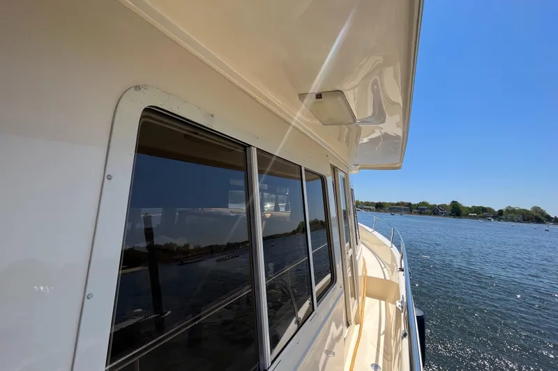 Slide: The Image of 2005 Mainship 400 Trawler side view on water, showcasing windows and deck. - 17