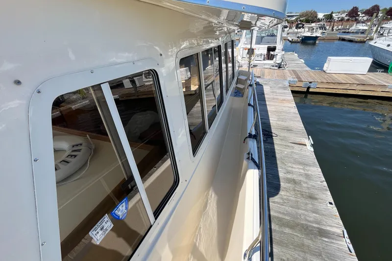 Slide: The Image of 2005 Mainship 400 Trawler docked at a marina, showcasing side view and windows. - 18