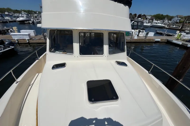 Slide: The Image of 2005 Mainship 400 Trawler docked at marina, showcasing front deck and windows. - 22