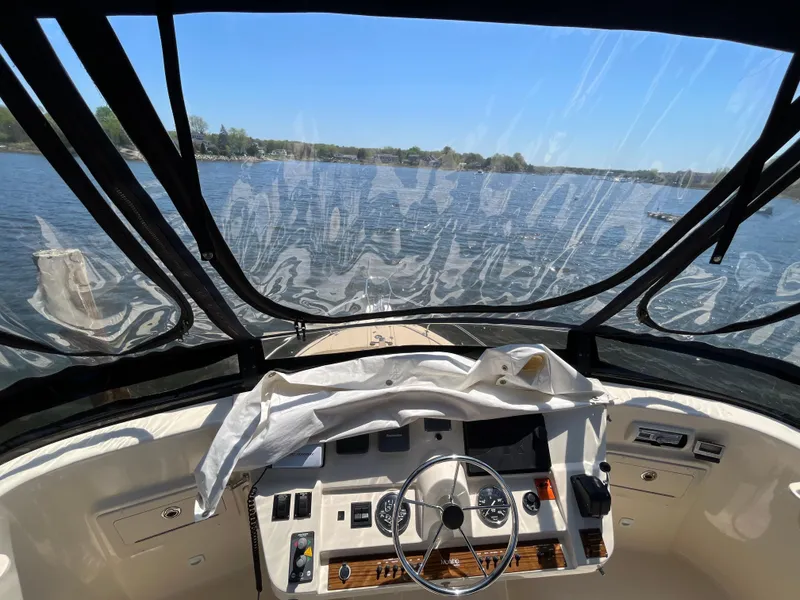 Slide: The Image of 2005 Mainship 400 Trawler helm view with clear canopy overlooking serene waters. - 35