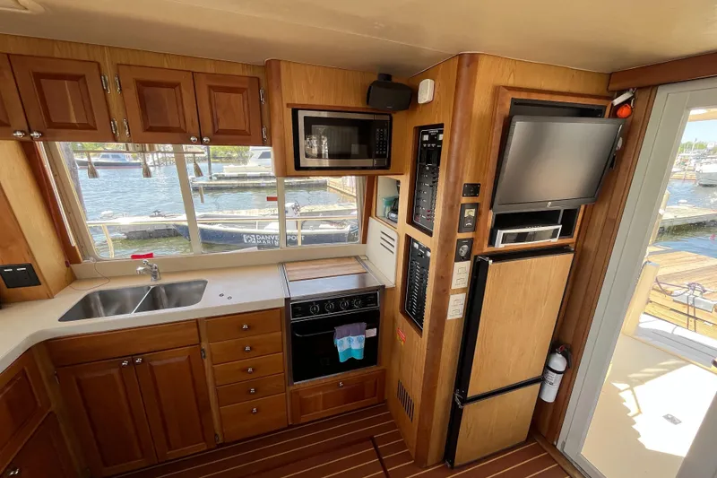 Slide: The Image of 2005 Mainship 400 Trawler kitchen with wood cabinetry, appliances, and marina view. - 40