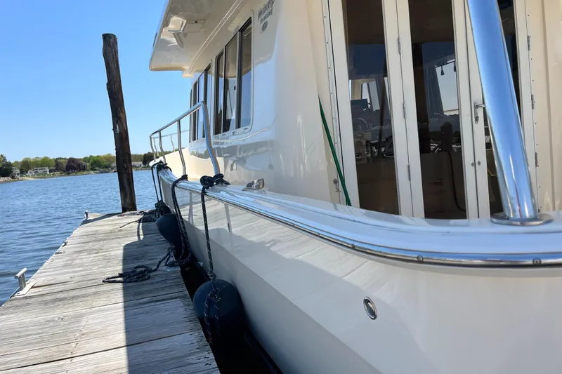 Slide: The Image of 2005 Mainship 400 Trawler docked by a serene waterfront. - 8