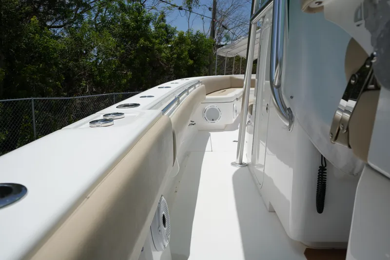 Slide: The Image of 2015 Contender 39ST boat deck with seating, rod holders, and railing, surrounded by greenery. - 9