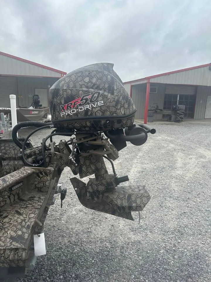 Slide: The Image of 2025 Pro-Drive 2054 X Series TD outboard motor with camouflage design in a gravel lot. - 4