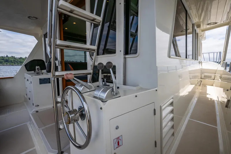 Slide: The Image of 1997 Offshore Yachts 52 Sedan helm with steering wheel and controls, docked on a sunny day. - 35