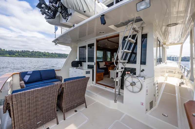 Slide: The Image of 1997 Offshore Yachts 52 Sedan with outdoor seating and ladder, docked on a serene waterway. - 36