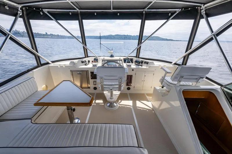 Slide: The Image of 1997 Offshore Yachts 52 Sedan cockpit with seating, table, and helm, overlooking serene waters. - 42