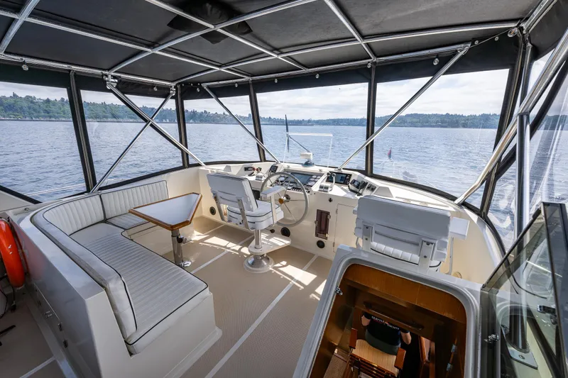 Slide: The Image of 1997 Offshore Yachts 52 Sedan helm with panoramic windows and seating, overlooking serene waters. - 43