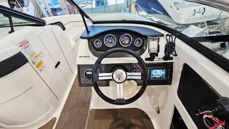 Slide: The Image of 2014 Sea Ray 220 Sundeck Outboard dashboard with steering wheel and gauges. - 12