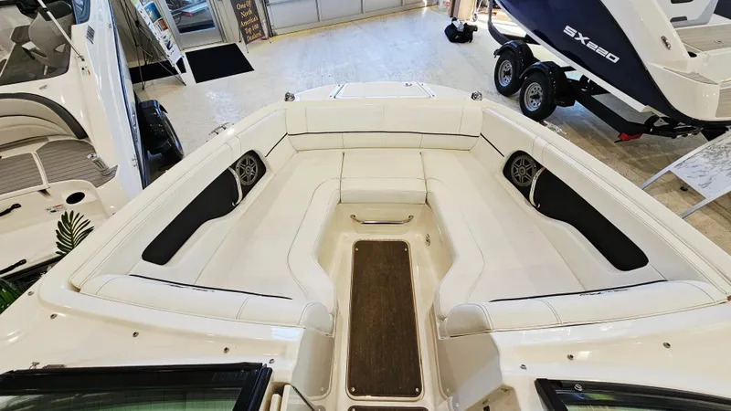 Slide: The Image of 2014 Sea Ray 220 Sundeck Outboard interior with white seating and wood accents. - 16