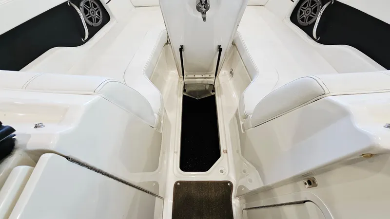 Slide: The Image of 2014 Sea Ray 220 Sundeck Outboard interior with white seating and storage compartments. - 22