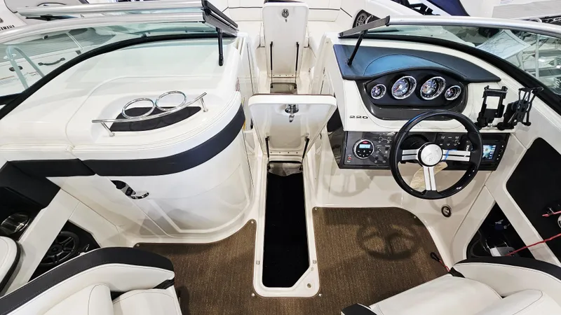 Slide: The Image of 2014 Sea Ray 220 Sundeck Outboard interior with steering wheel and dashboard controls. - 23