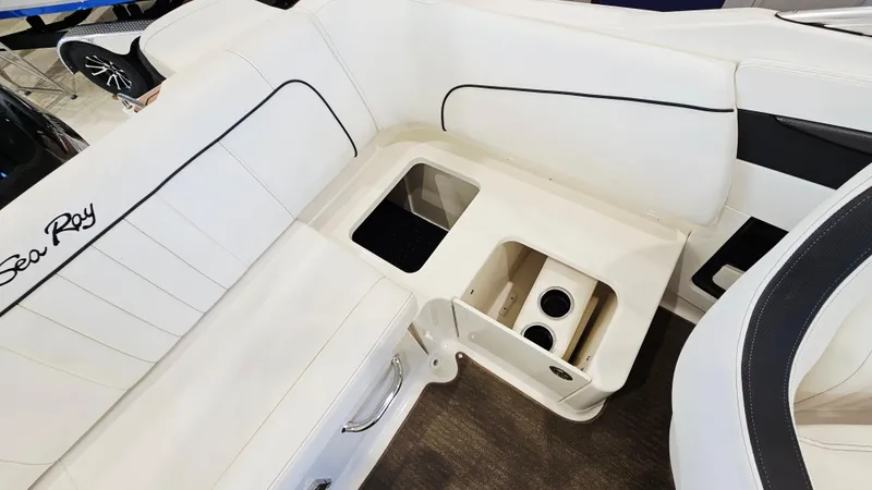 Slide: The Image of 2014 Sea Ray 220 Sundeck Outboard interior with white seating and storage compartments. - 24