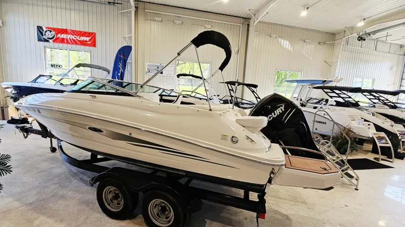 Slide: The Image of 2014 Sea Ray 220 Sundeck Outboard boat displayed indoors on a trailer. - 4