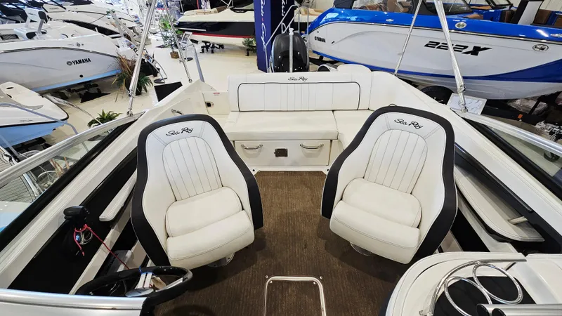 Slide: The Image of 2014 Sea Ray 220 Sundeck Outboard interior with white seating and steering wheel. - 6