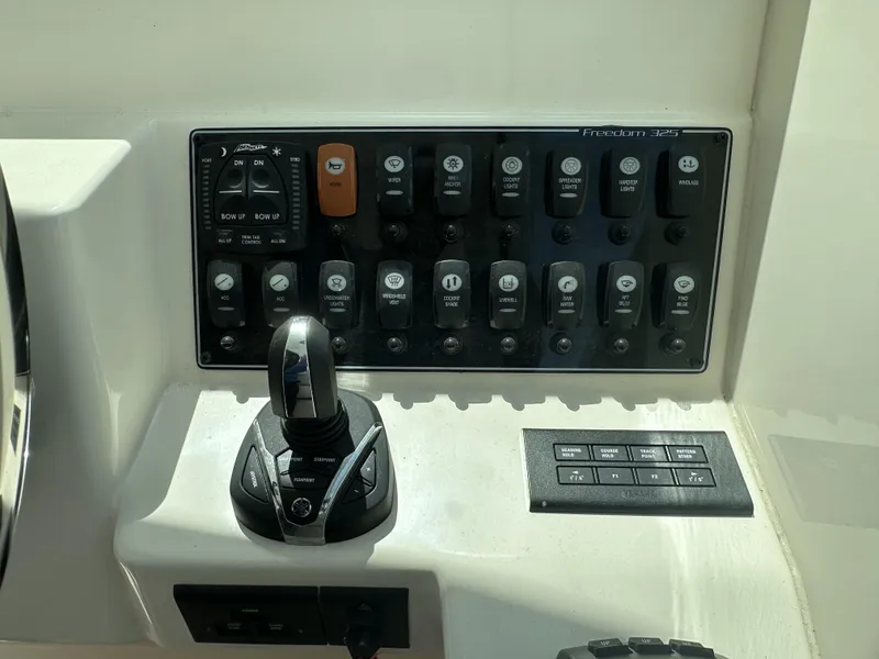 Slide: The Image of Control panel of 2023 Grady-White Freedom 325 boat with switches and joystick. - 17