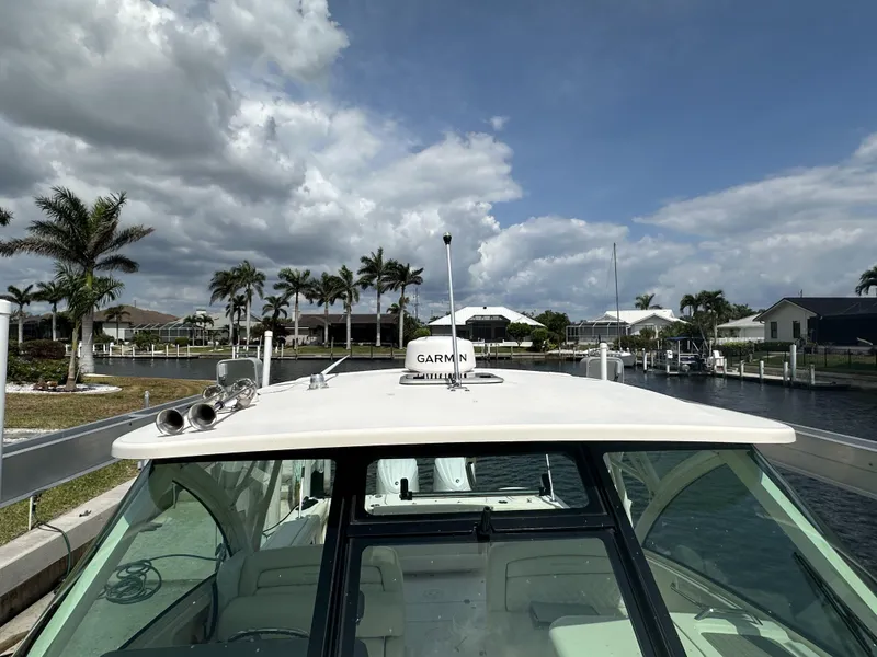 Slide: The Image of 2023 Grady-White Freedom 325 boat docked near palm trees under cloudy sky. - 21