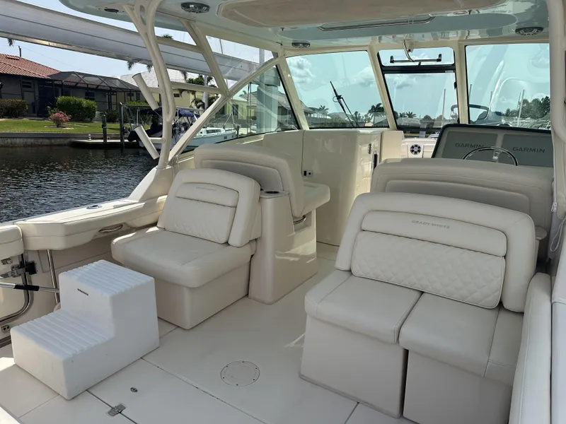 Slide: The Image of 2023 Grady-White Freedom 325 boat interior with plush seating and helm, docked by the water. - 7