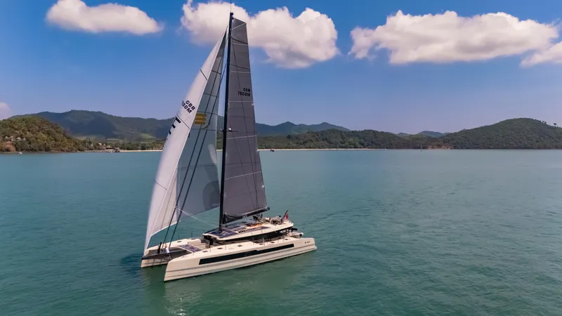 Slide: The Image of 2026 McConaghy MC75 catamaran sailing on calm waters under a clear blue sky. - 2