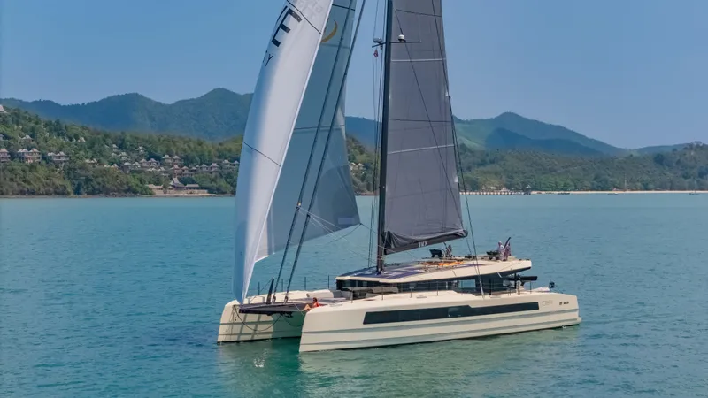Slide: The Image of 2026 McConaghy MC75 catamaran sailing on calm waters with scenic mountain backdrop. - 8