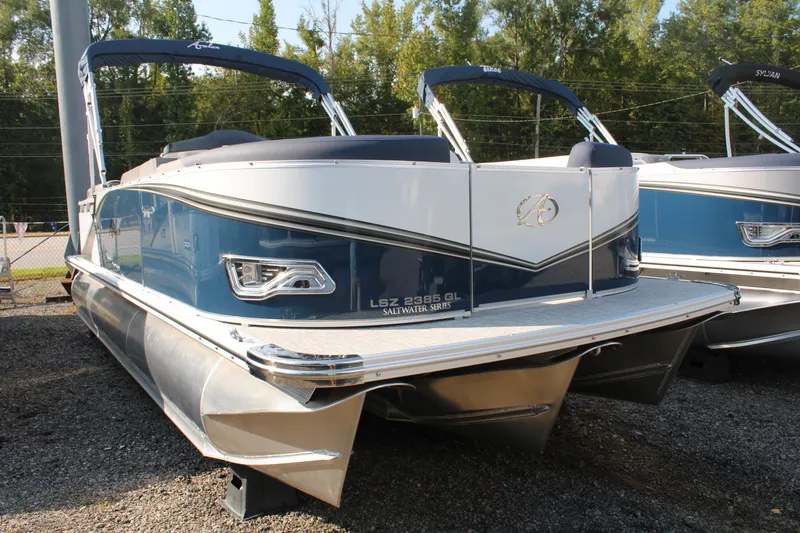 Slide: The Image of 2024 Avalon LSZ Quad Lounger pontoon boat, blue and white, parked outdoors. - 11