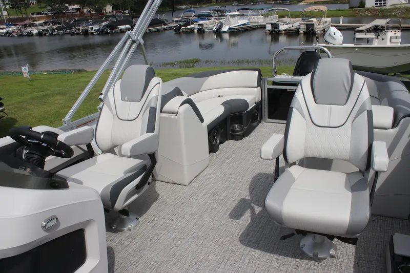 Slide: The Image of 2025 Avalon LSZ Quad Lounger interior with plush seating, steering console, and waterfront view. - 2