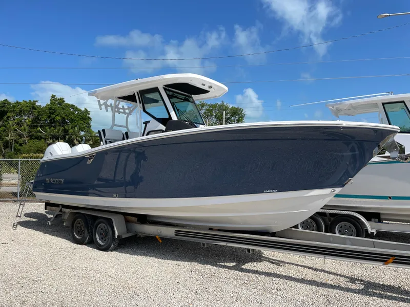 The Image of 2025 Blackfin 272CC boat on trailer under clear blue sky. - 1