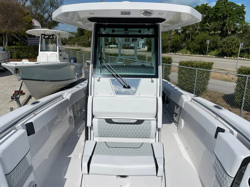 Slide: The Image of 2025 Blackfin 272CC boat interior with seating and console, docked outdoors. - 19