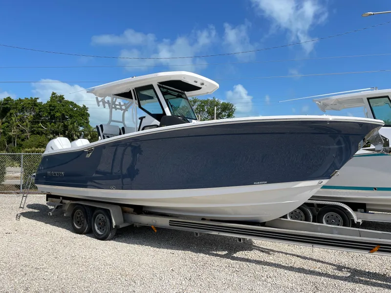 Slide: The Image of 2025 Blackfin 272CC boat on trailer under clear blue sky. - 3