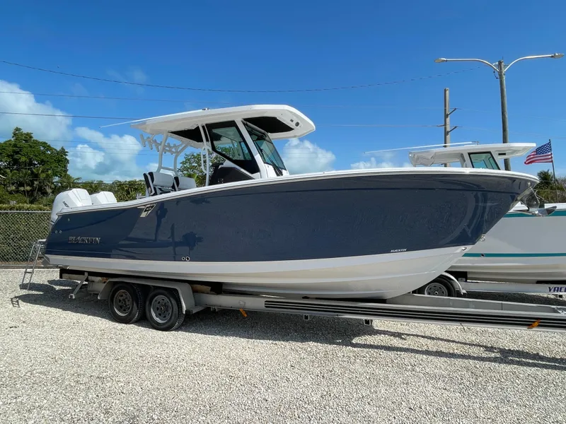 Slide: The Image of 2025 Blackfin 272CC boat on trailer, parked outdoors under clear blue sky. - 42